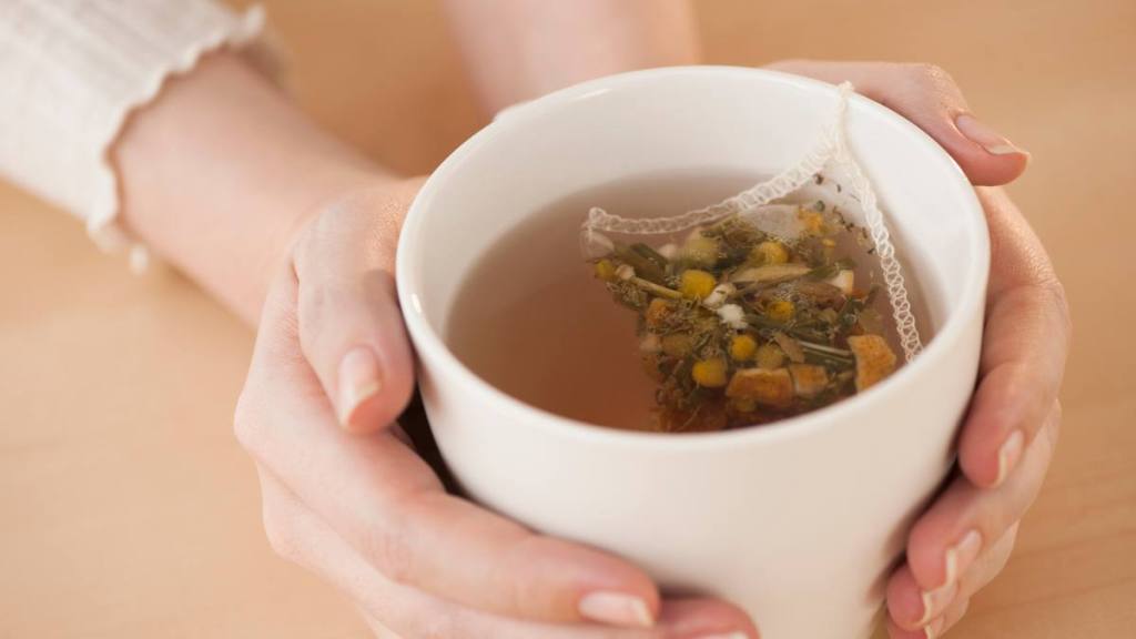 tea for headaches: Woman holding cup with chamomile tea