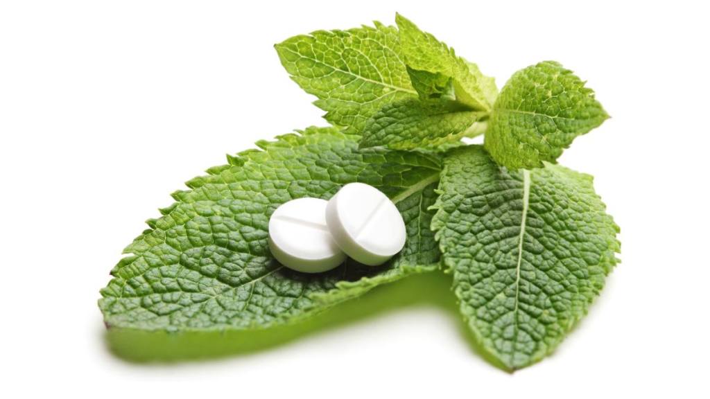 White pills on a green leaves of mint 