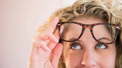 How to fix scratched glasses: Woman wearing glasses, looking up in thought