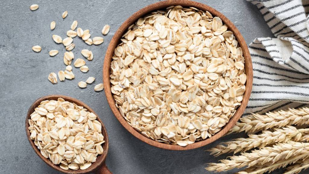 refined sugar: Oats, rolled oats or oat flakes in wooden bowl and wooden spoon. Top view. Healthy grains, low carb diet food