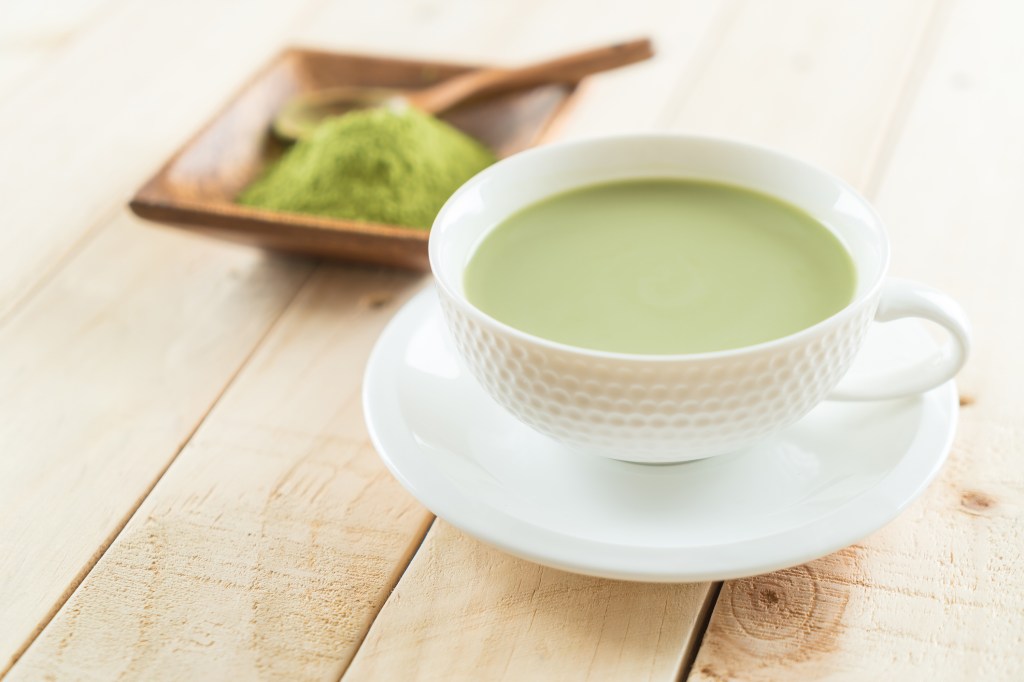 green matcha powder next to cup of green tea for matcha benefits for skin