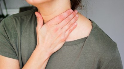 woman holding sore throat after strep