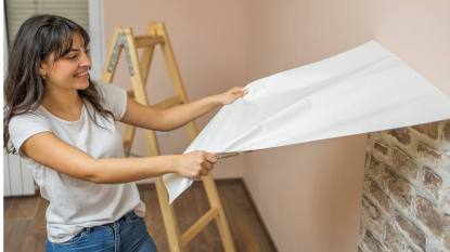 How to remove wallpaper: Young girl takes the wallpaper off the wall before painting the wall.