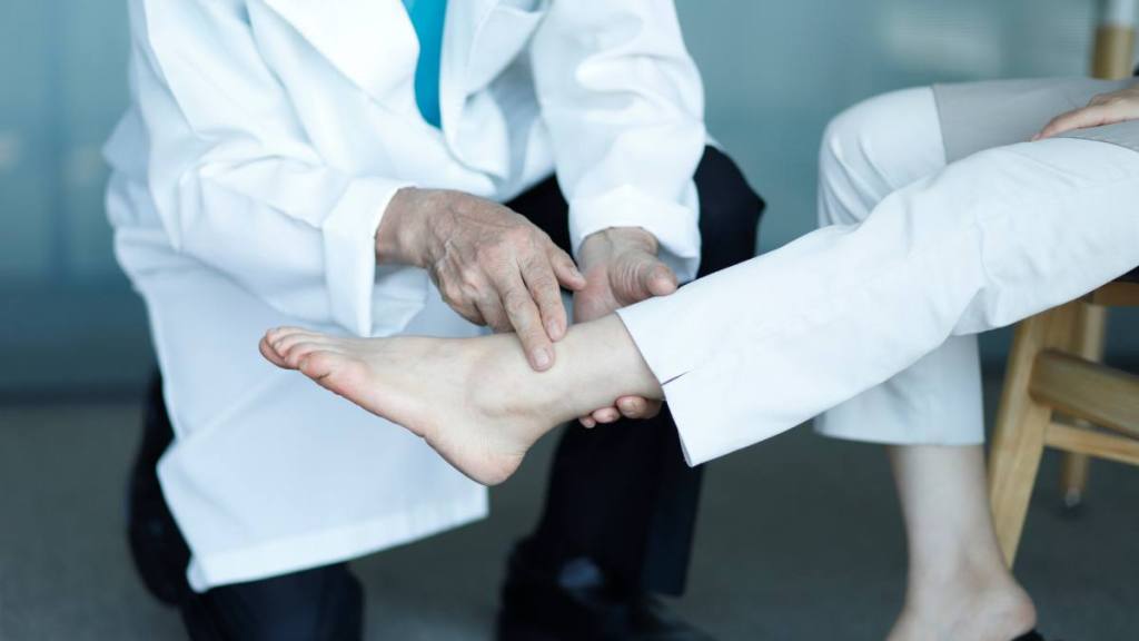 Toe cramps: Oriental medicine doctor checking patient's ankle pain