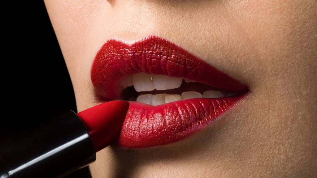 uses for sugar: Female applying red lipstick, close up