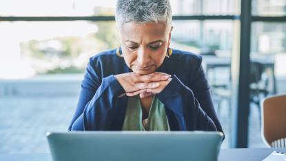 How to protect your identity: Sad, unhappy and tired business woman browsing online on a laptop, reading an email with bad news or suffering from burnout while sitting in an office. Mature female boss dealing with a work problem