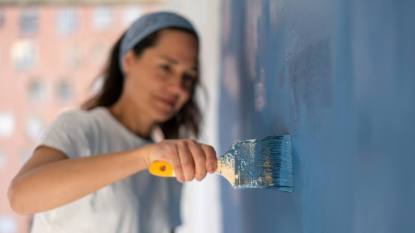 how to paint over wallpaper: Close-up on a woman painting her house