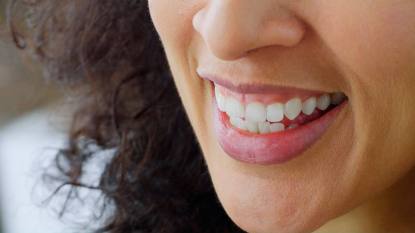 Menopause and oral health: Close-up of smiling woman with pink lips.