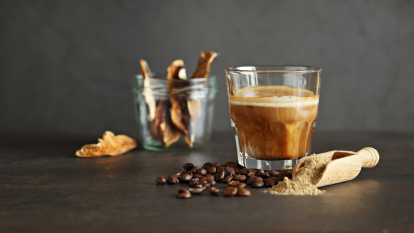Mushroom coffee in a glass, coffee beans and dry mushrooms on a dark background