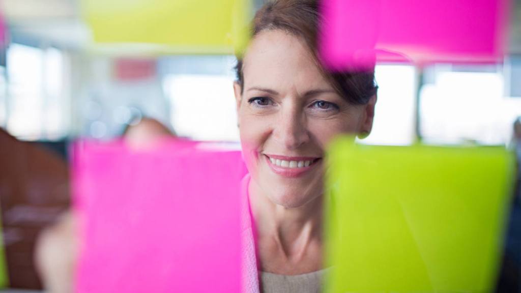 woman looking at post it notes ; happy and healthy 
