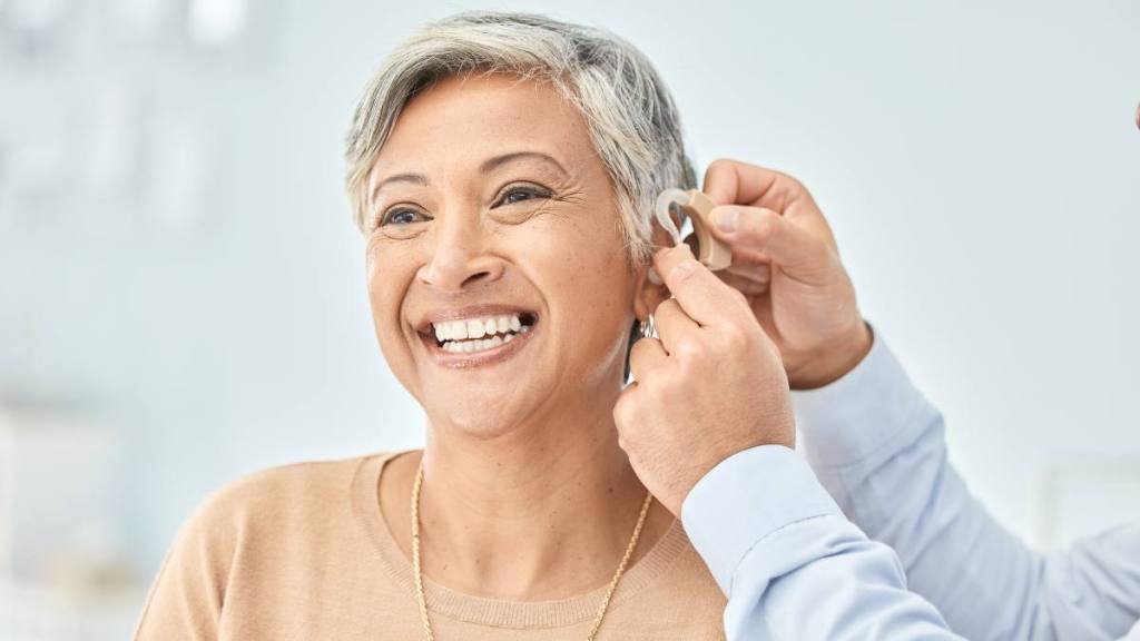 woman getting fitted for hearing aid; super agers