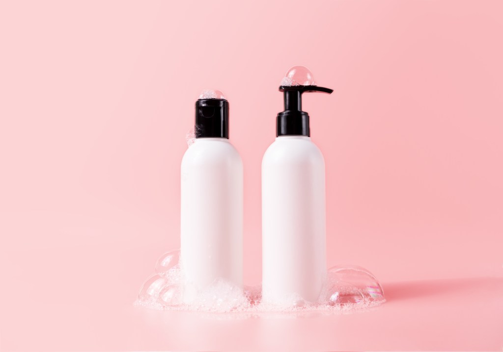 shampoo and conditioner bottles against pink background