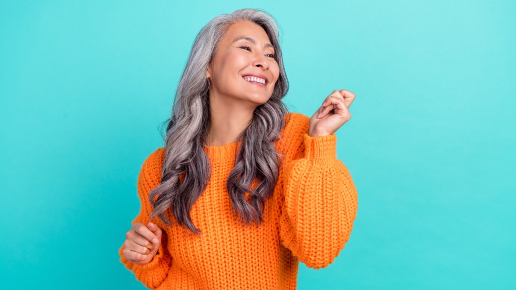 A woman with long hair wearing an orange sweater who is dancing to reverse prediabetes
