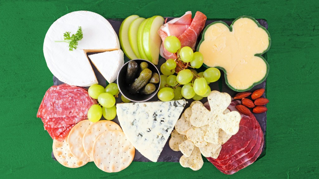 Snacks for St Patrick's Day: Irish cheeses, deli meats, crackers, almonds and a bowl of mini pickles arranged on a slate serving board