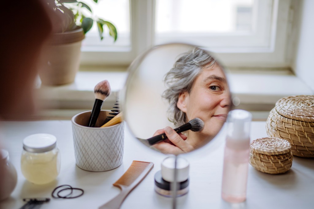 mature woman applying skincare makeup