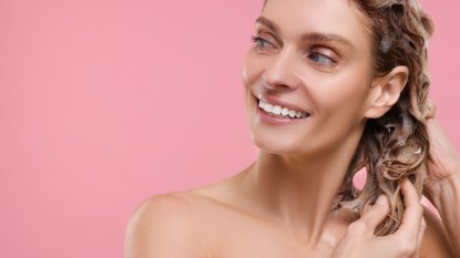 mature woman smiling while applying shampoo before conditioner