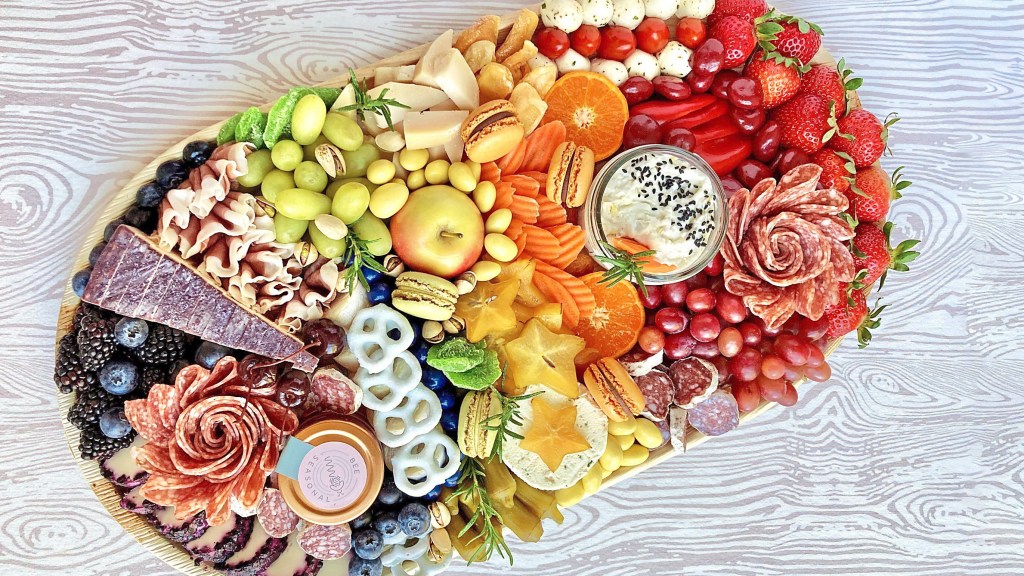 Snacks for St Patrick's Day: Colorful sweet and savory charcuterie board filled with fruit, nuts, veggies, meats, cheeses and sweet bite-sized treats to form a rainbow of colors