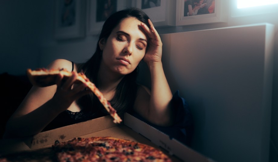 Tired and disappointed woman eating pizza