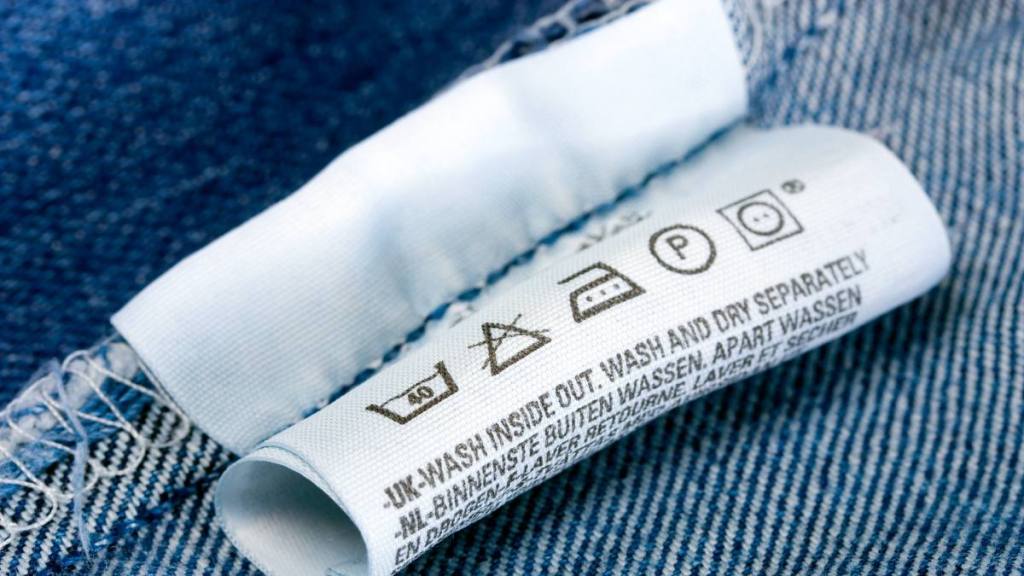 How to wash jeans: Label clothes - Laundry advice care symbols description , jeans blue background