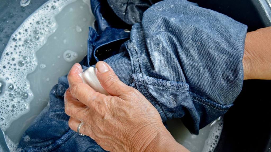 How to wash jeans: A person washing clothes with soap