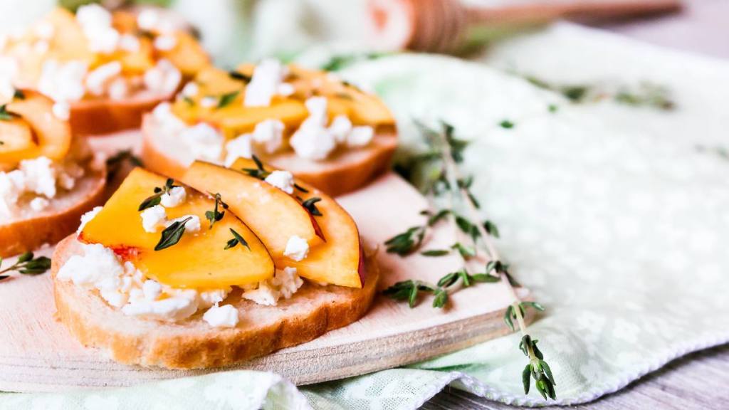 cottage cheese trend: Homemade Bruschetta with nectarines, salted feta cheese, dried thyme and honey on a wooden board, selective focus