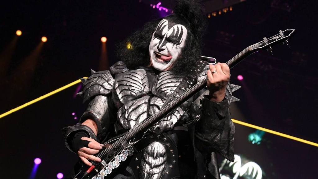 Man on guitar with tongue out; kiss band members