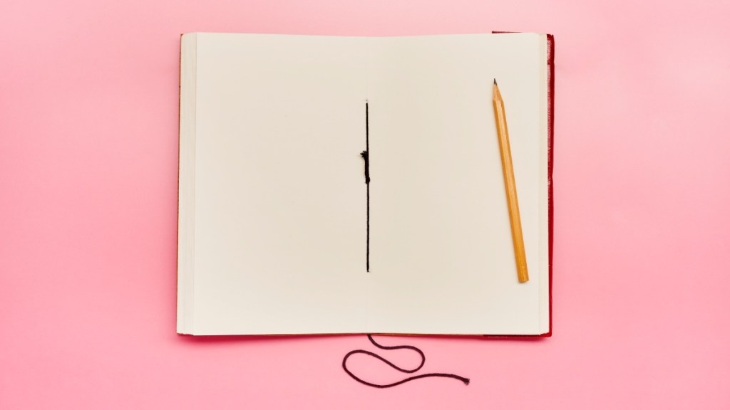 A notebook and pencil on a pink background