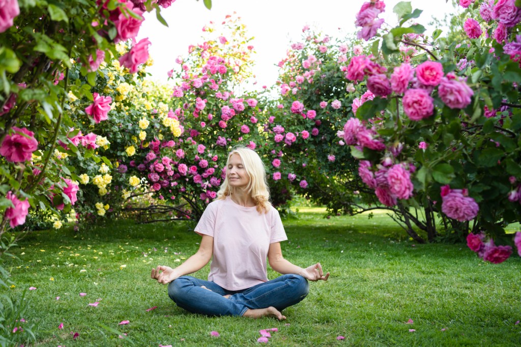 Woman meditating in rose garden, nature and happiness