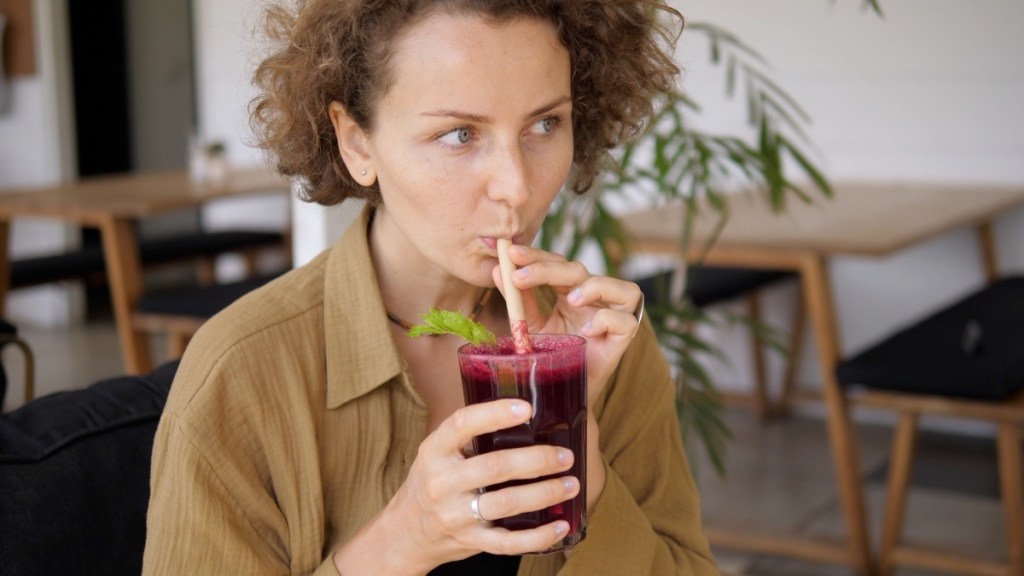A woman sipping a beet juice drink to lower blood pressure quickly