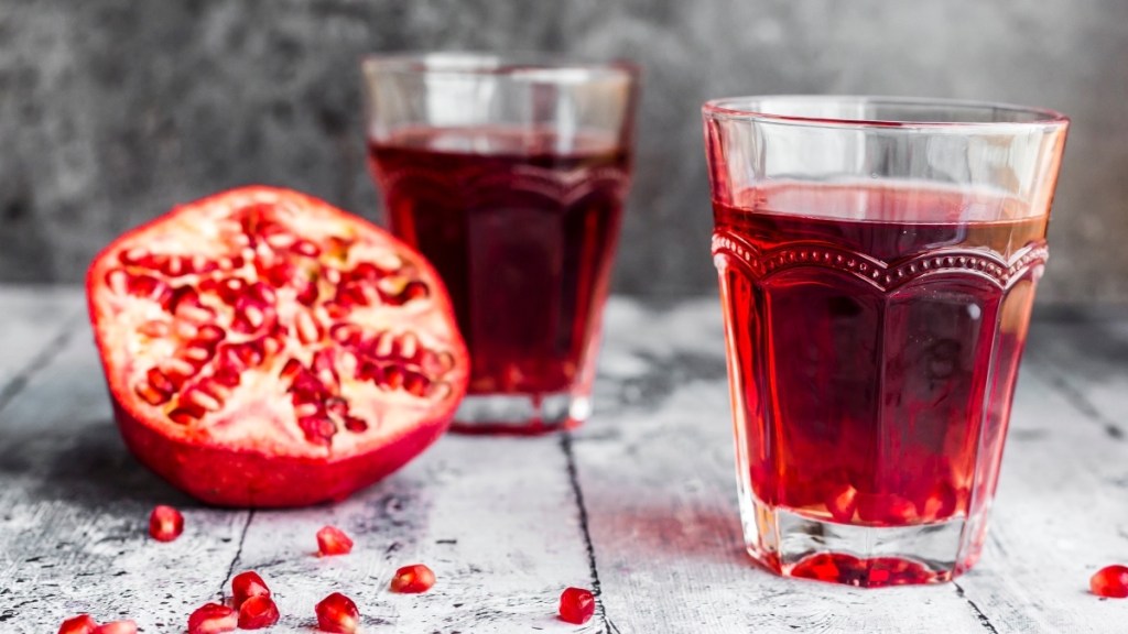 Two glasses of pomegranate juice next to fresh pomegranate