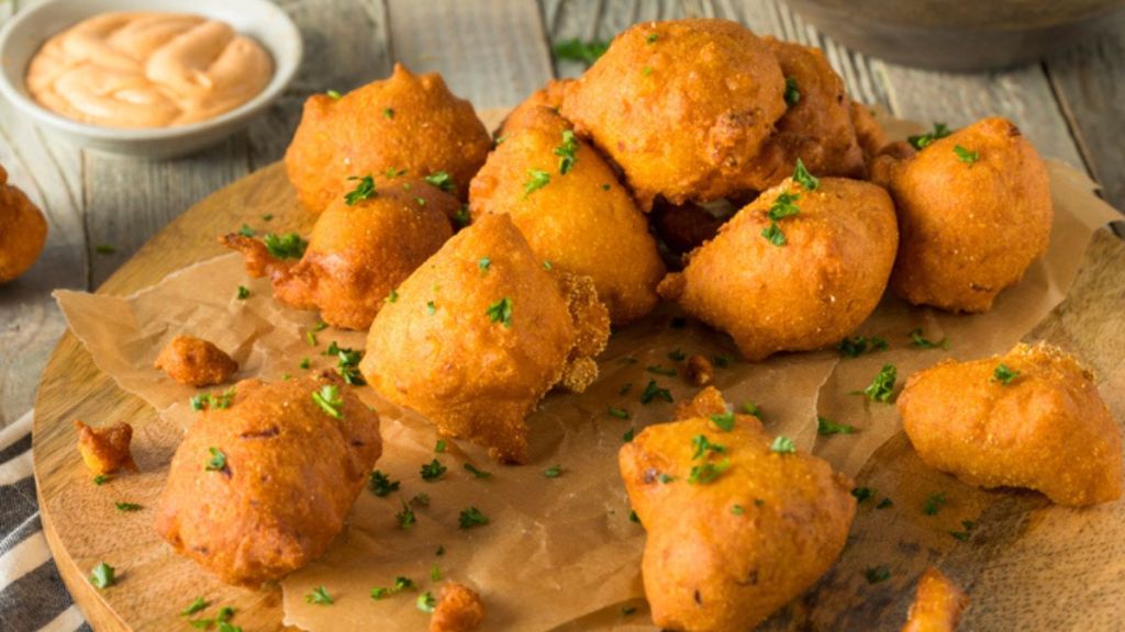 air fryer hush puppies recipe: hush puppies with parsley on wooden board with dipping sauce