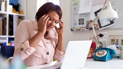 mature woman stressed at her desk in front of laptop