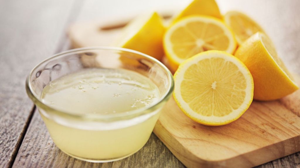 overnight cleaning hacks: lemon juice in small bowl with fresh cut lemons on wooden board