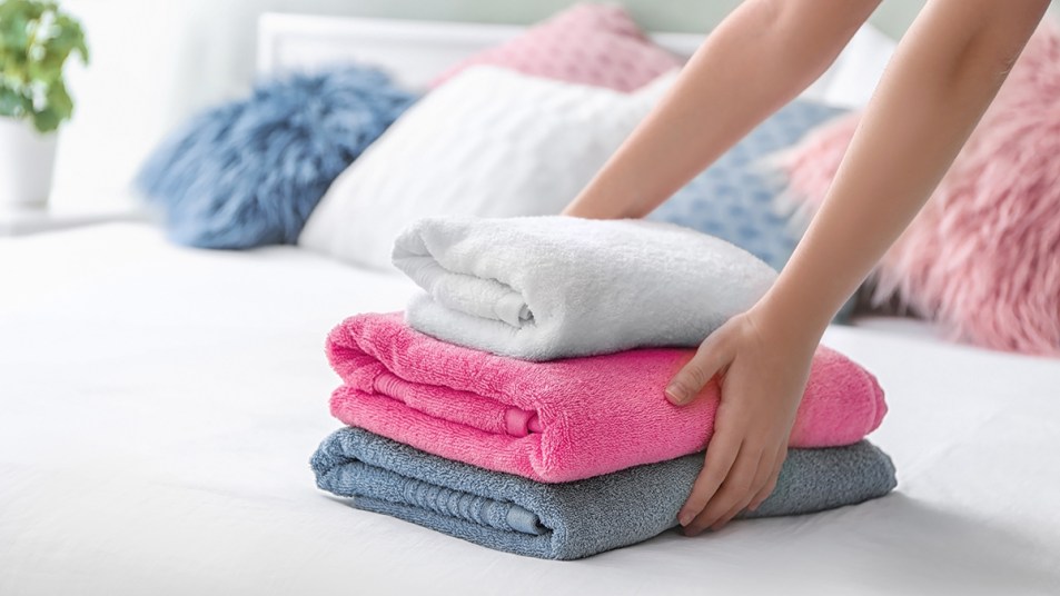 Woman's hands placing stacked towels on a bed