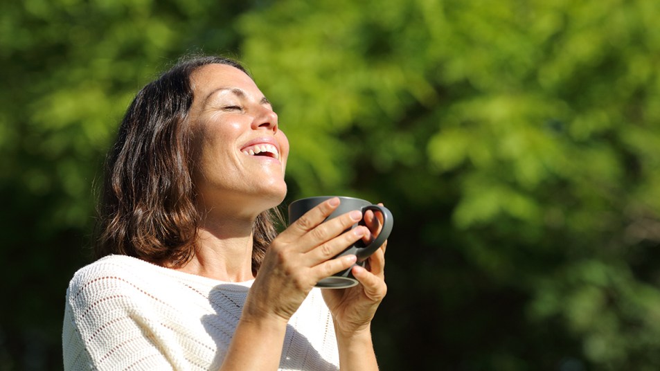 A woman feeling peaceful with her morning coffee because she lowered cortisol