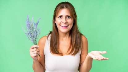 A middle-aged woman holding up a sprig that looks like red sage