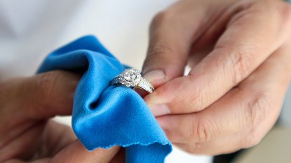 Two hands polishing an engagement ring, which is one of the uses of club soda