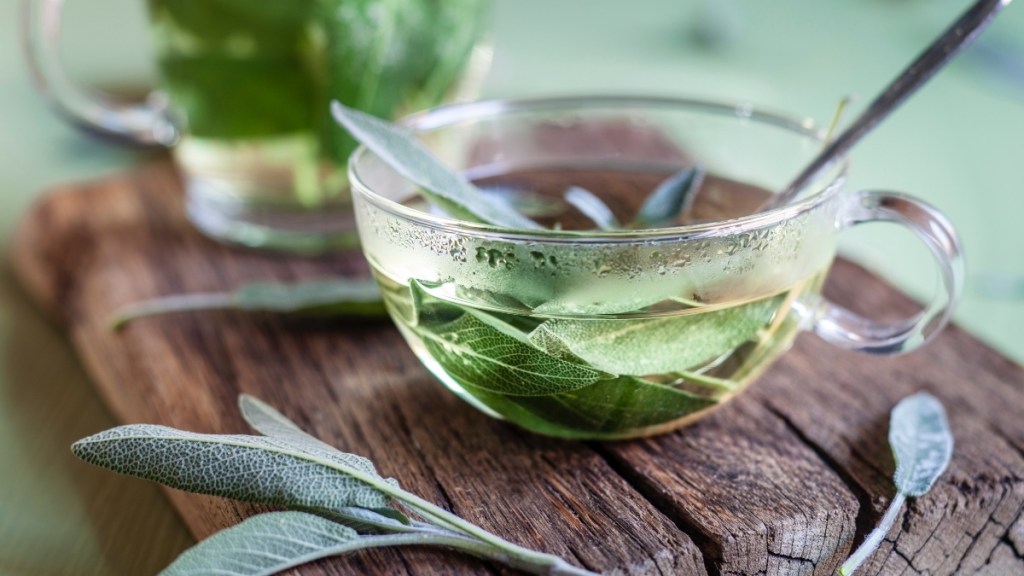 A clear glass of hot flash-fighting sage tea with sage leaves inside