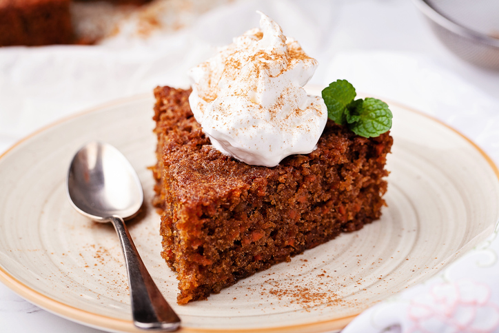Slice of carrot cake topped with whipped cream.