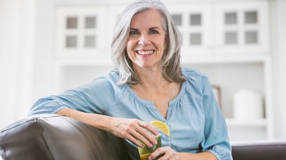 A smiling older woman drinking one of the foods that help stop hot flashes