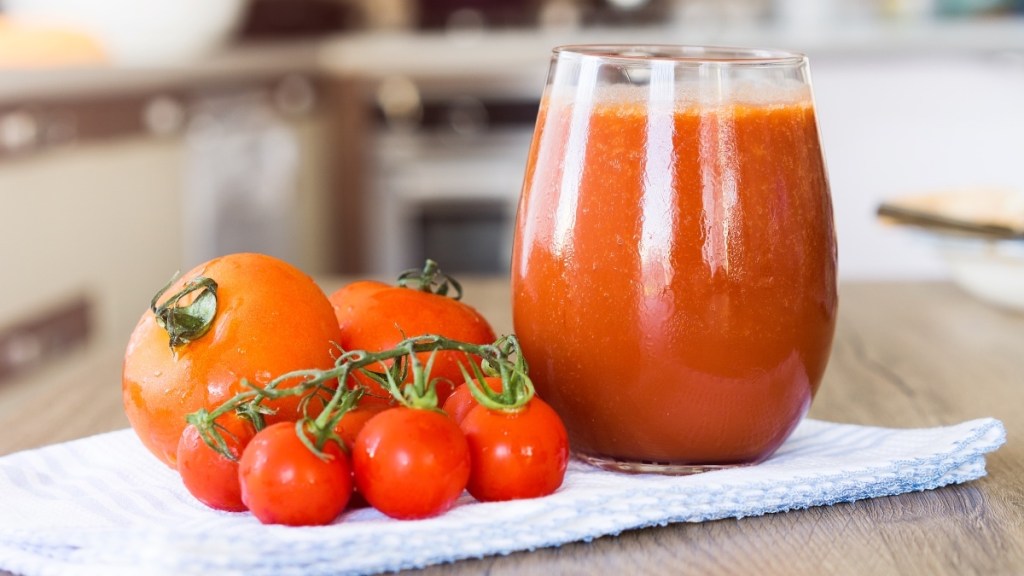 A glass of tomato juice next to tomatoes, which is used to fight hot flashes