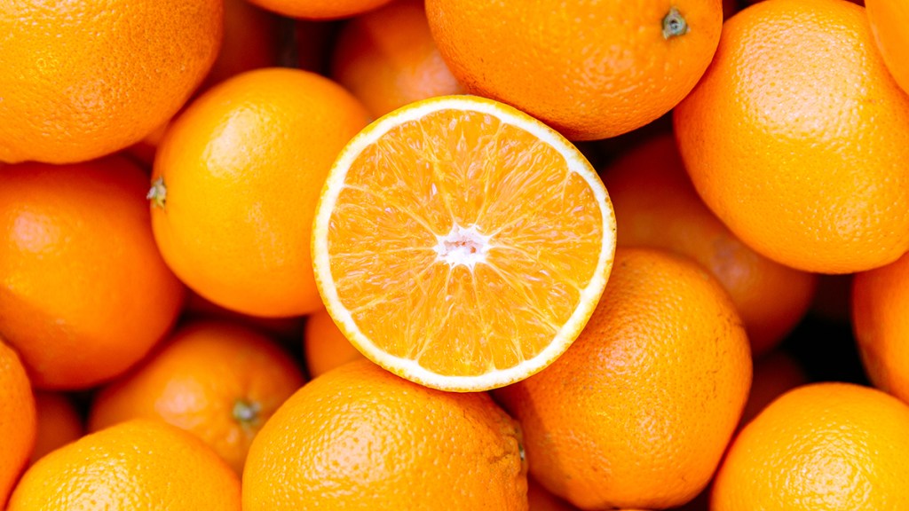 Oranges piled up with one cut in half to reveal its fragrant essential oil