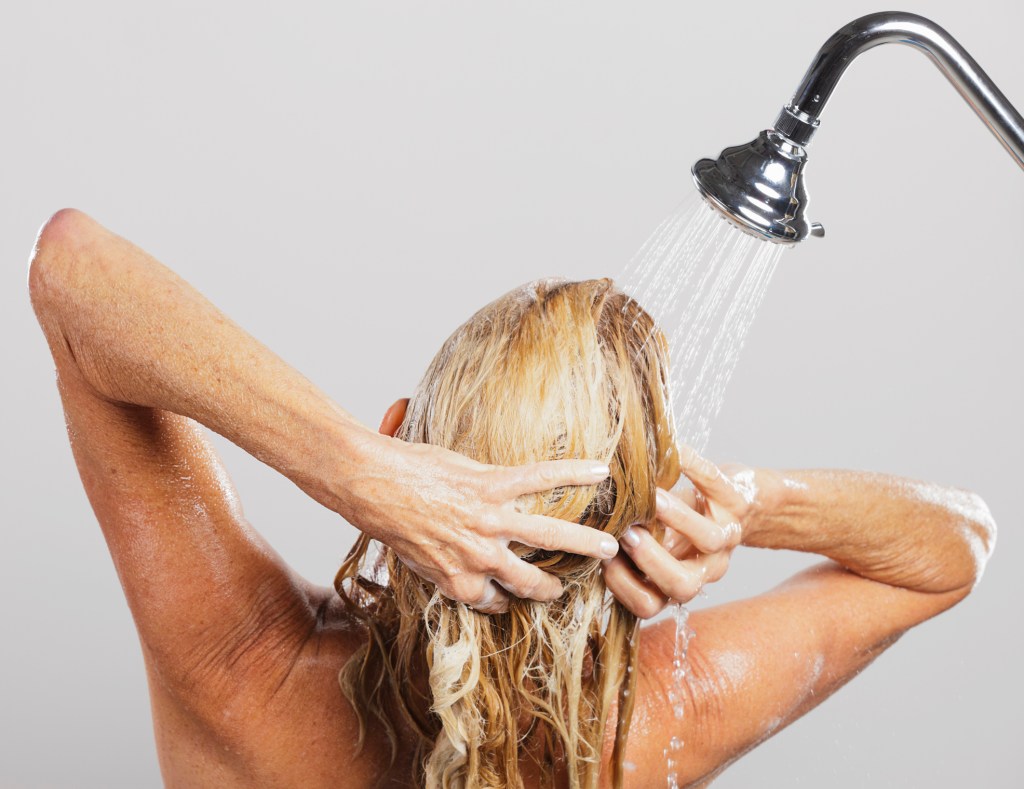 Back of head of mature woman washing hair in shower