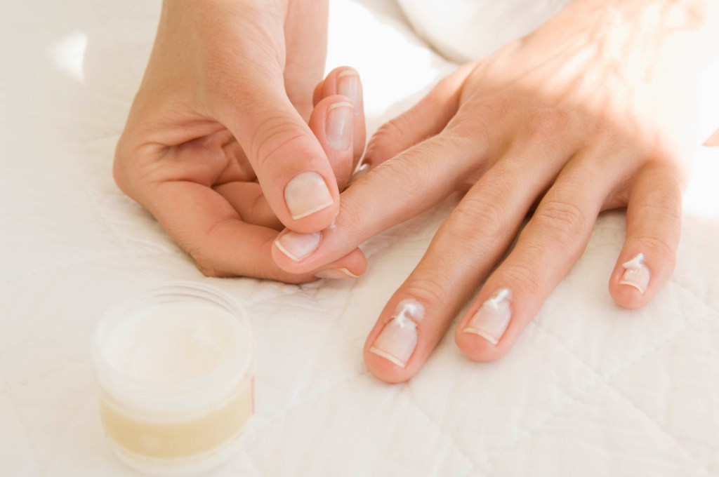 A woman applying a hydrating cream to her cuticles