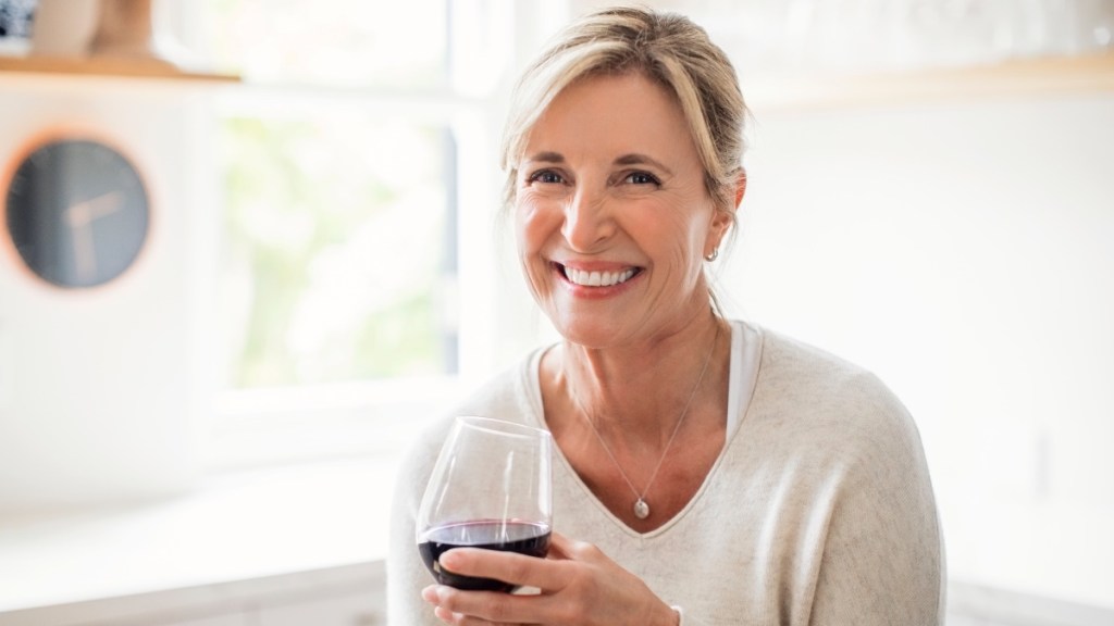 A woman with a glass of wine before bed, which makes it hard to sleep