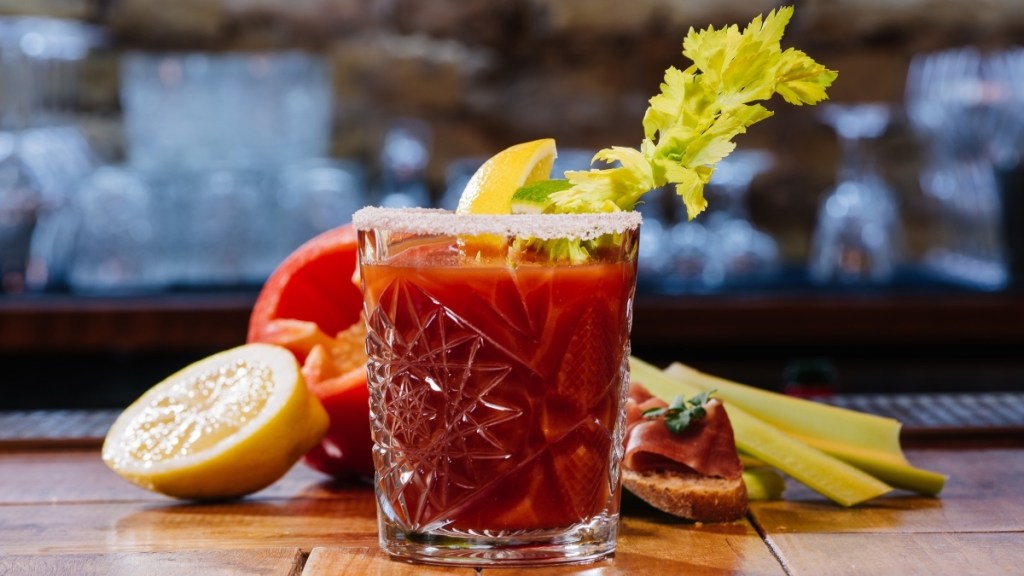A bloody Mary adrenal cocktail in a clear glass made with tomato juice and garnished with celery and lemon
