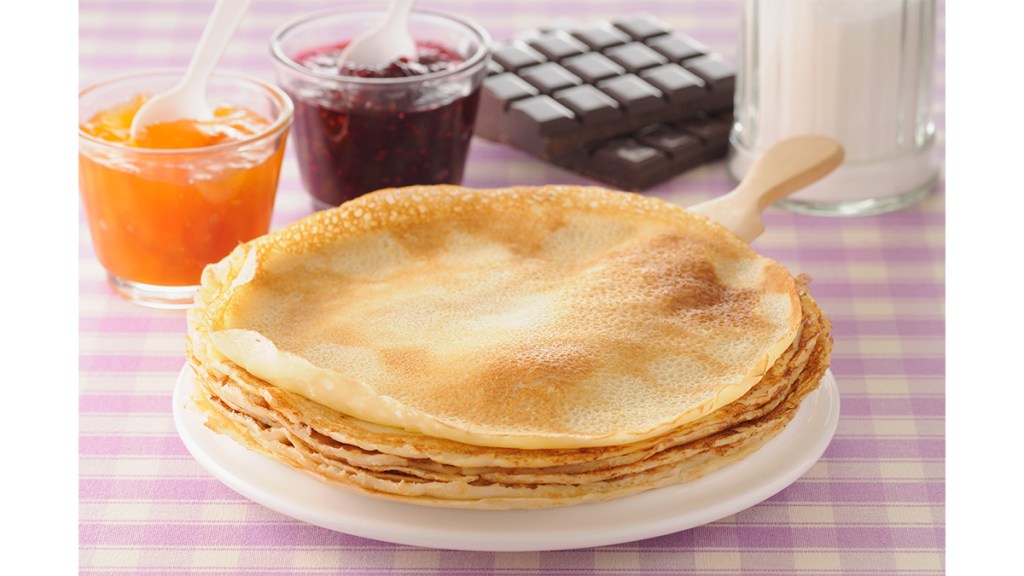 A plate with homemade crepes as part of a guide on how to make the French dish using pancake mix