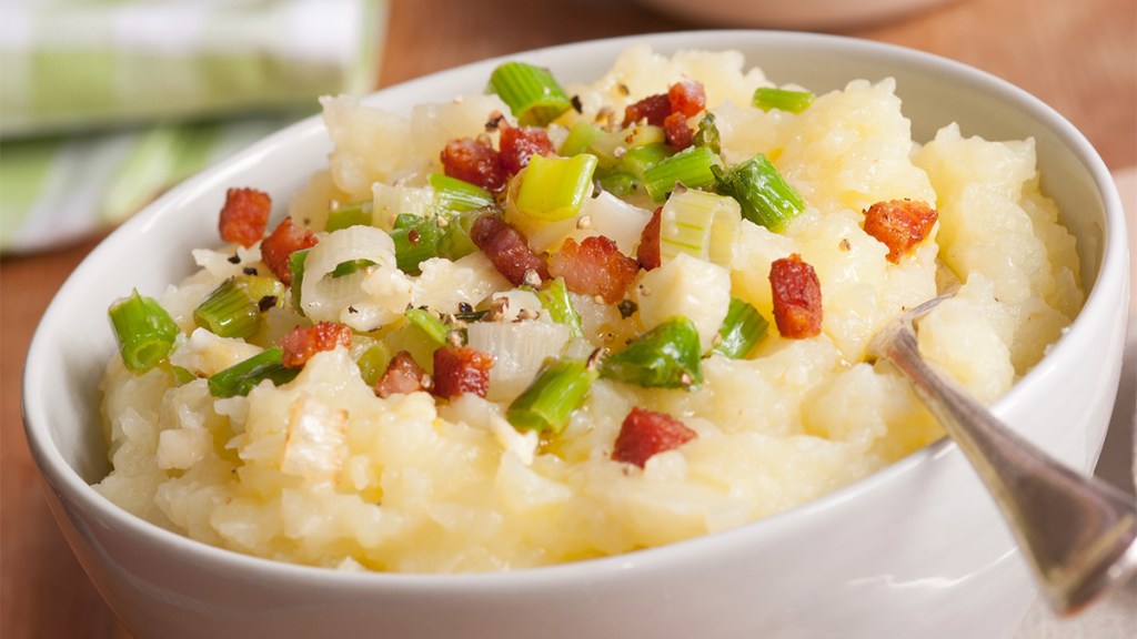 Mashed potatoes topped with onions and bacon bits as part of a guide on making a mashed potato bar