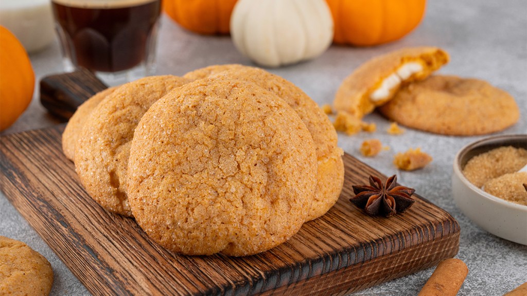 Pumpkin cheesecake cookies sitting on a wooden board