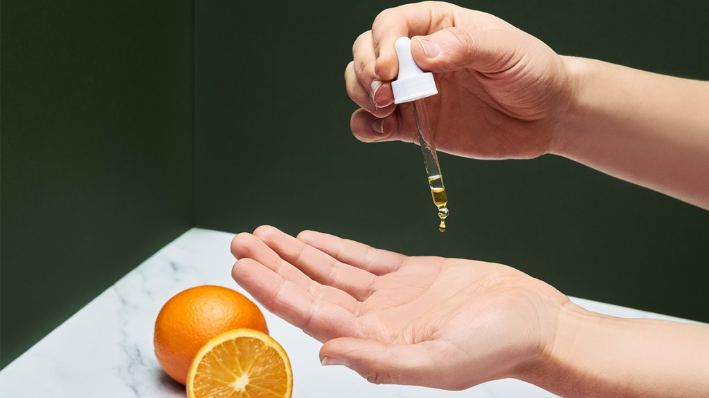 woman applying essential oil to her skin; orange essential oil benefits